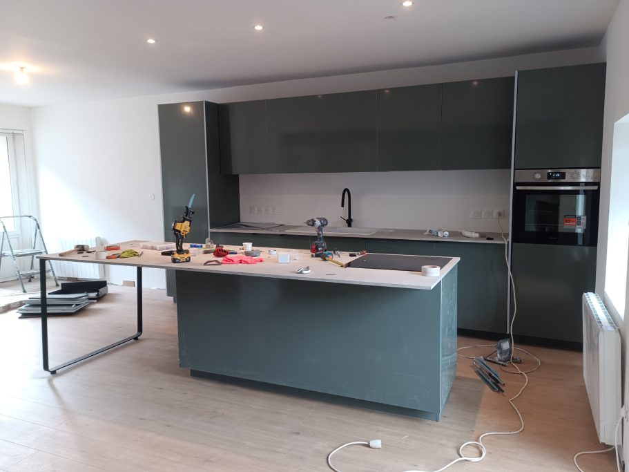 Cuisine moderne en cours de rénovation avec un îlot central et des outils éparpillés.