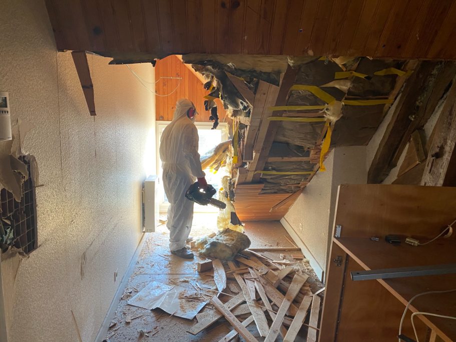 Un homme en vêtements de protection sur un chantier de démolition, déblayant des débris.