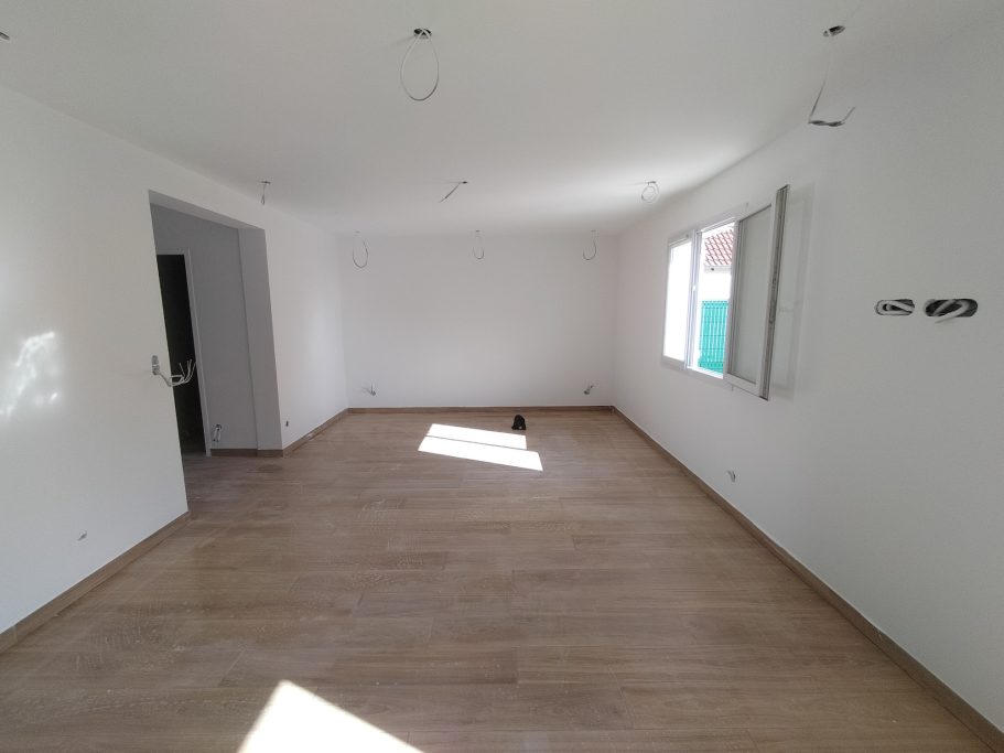 Intérieur d'une pièce vide avec sol en bois et lumière naturelle.